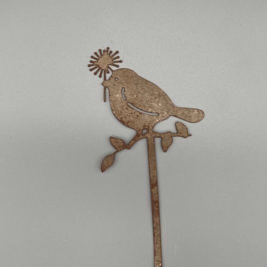 Ein Vogel mit Blume im Schnabel auf einem Ast in Rostoptik und eindimensional.