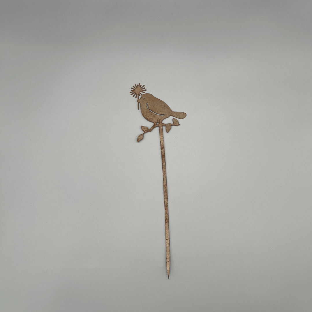 Liebevoll gestaltete Metallstecker zeigt einen Ast, auf dem ein Vogel mit Blume im Schnabel Platz genommen hat.