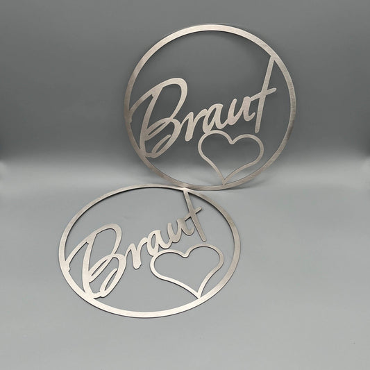 Zwei Dekoringe jeweils mit der Innenschrift Braut und einem Herz.