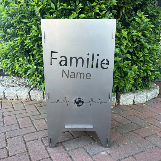 Seitenteil einer Feueronne mit Herzschlag für Fußball und einem Namen vor einer Hecke.