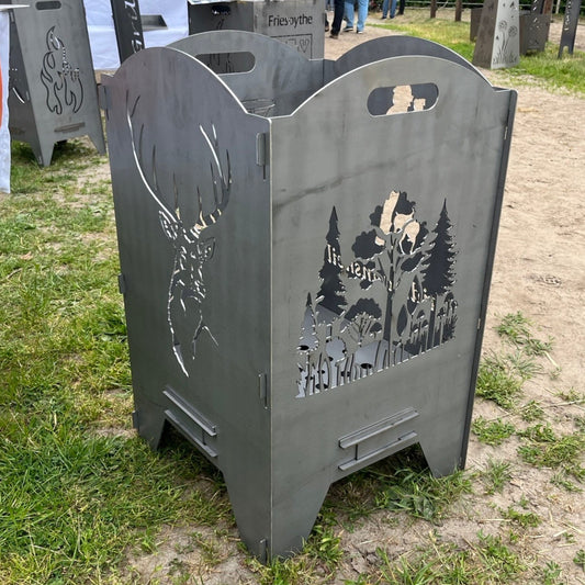 Feuertonne mit Hirschkopf auf der einen und einem Wald auf der anderen Seite.