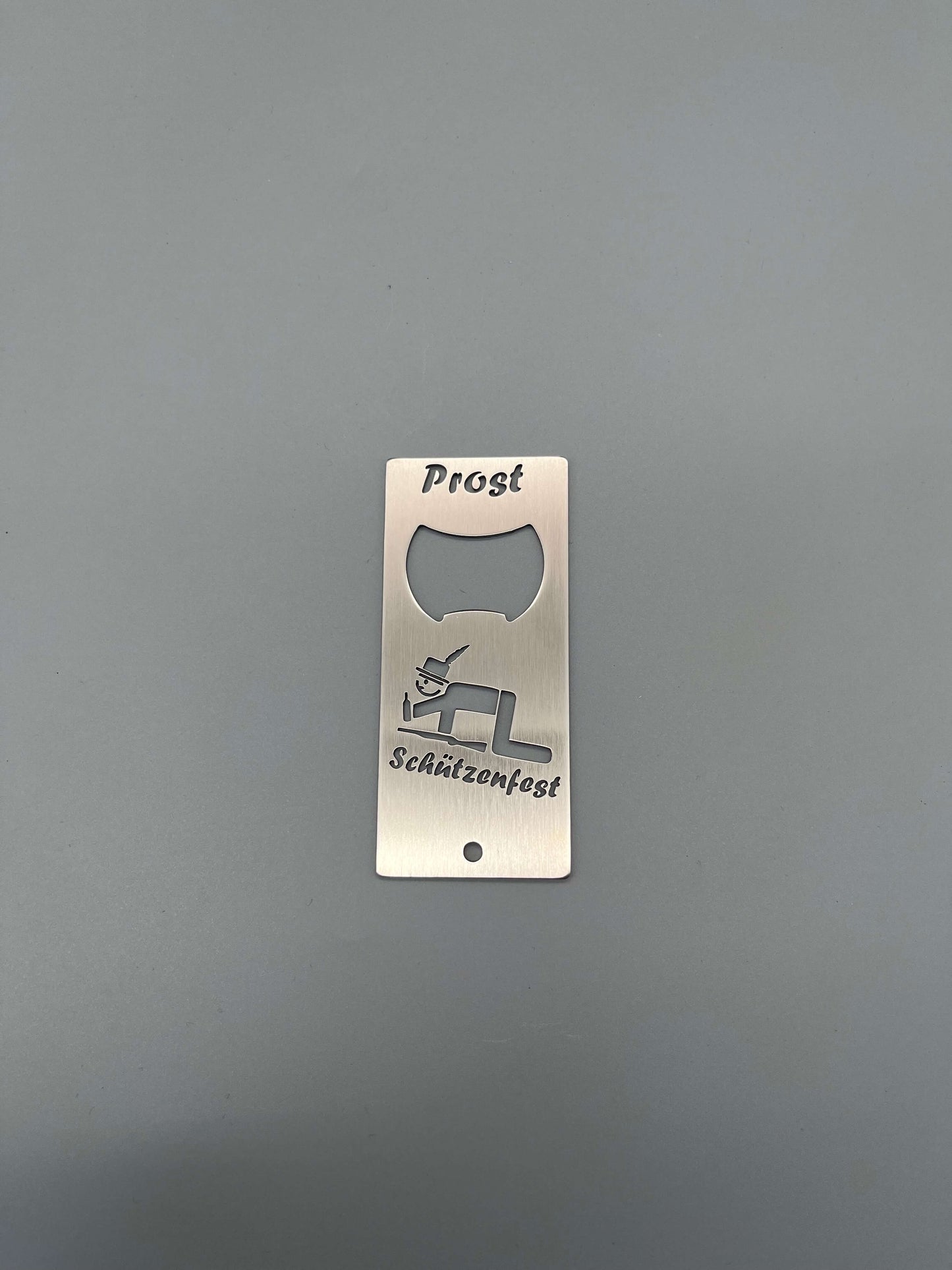 Rechteckiger silberner Flaschenöffner mit einem kriechenden Schützen und der Aufschrift Schützenfest