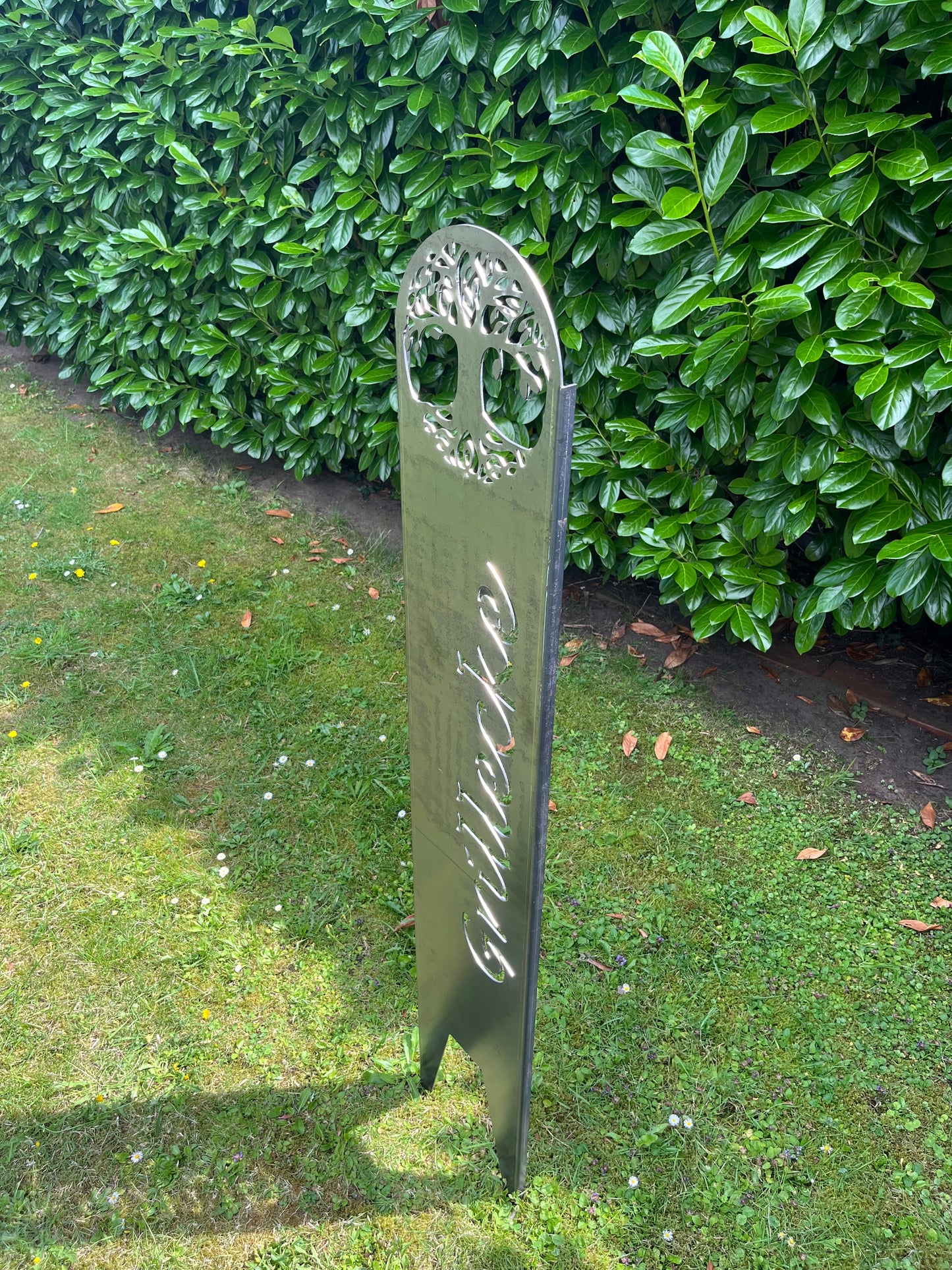 Seitenansicht im Garten auf einen Gartenstecker mit Schriftzug Grillecke