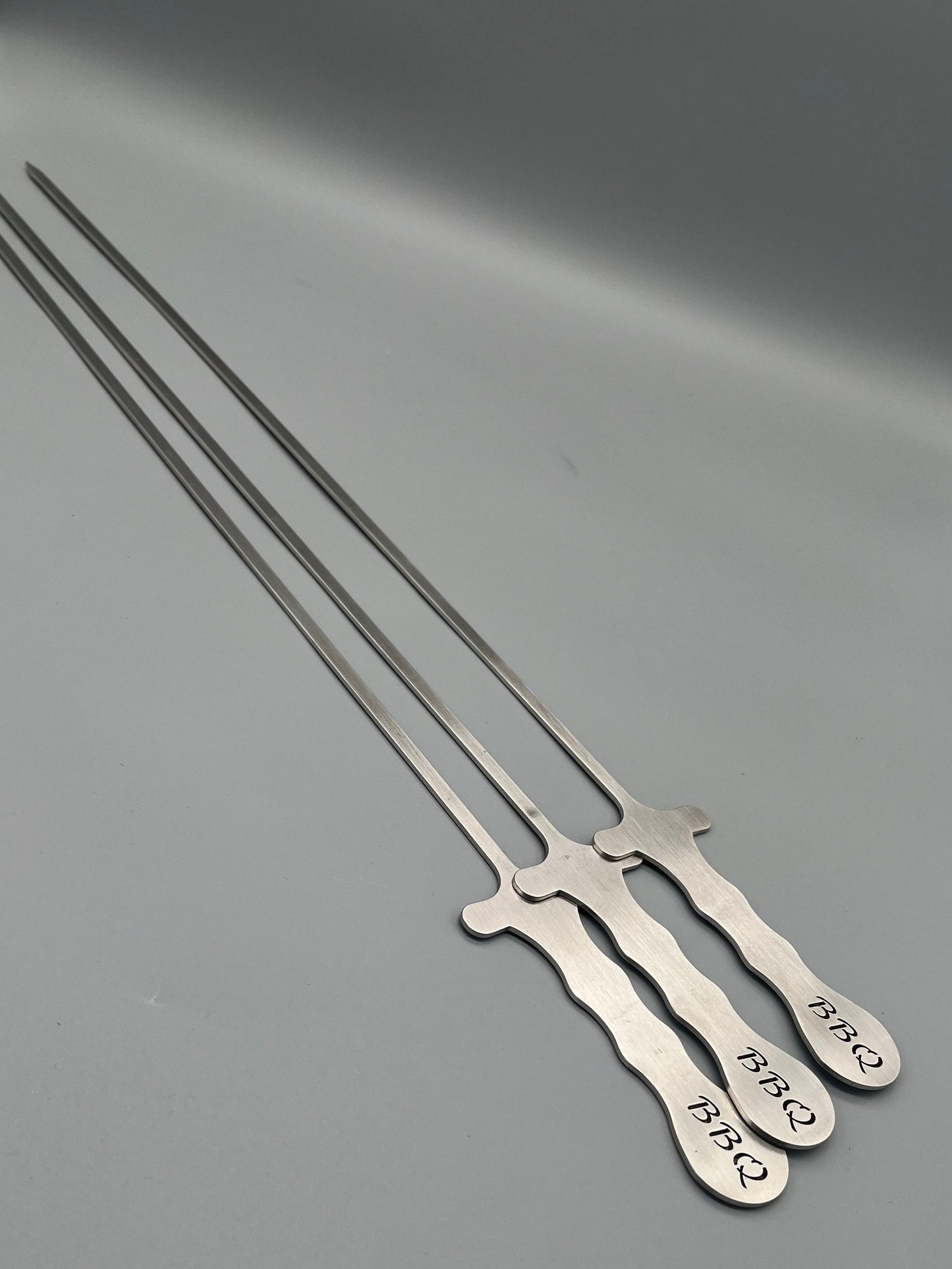 Drei lange Schaschlikspieße auf dem Griff steht BBQ