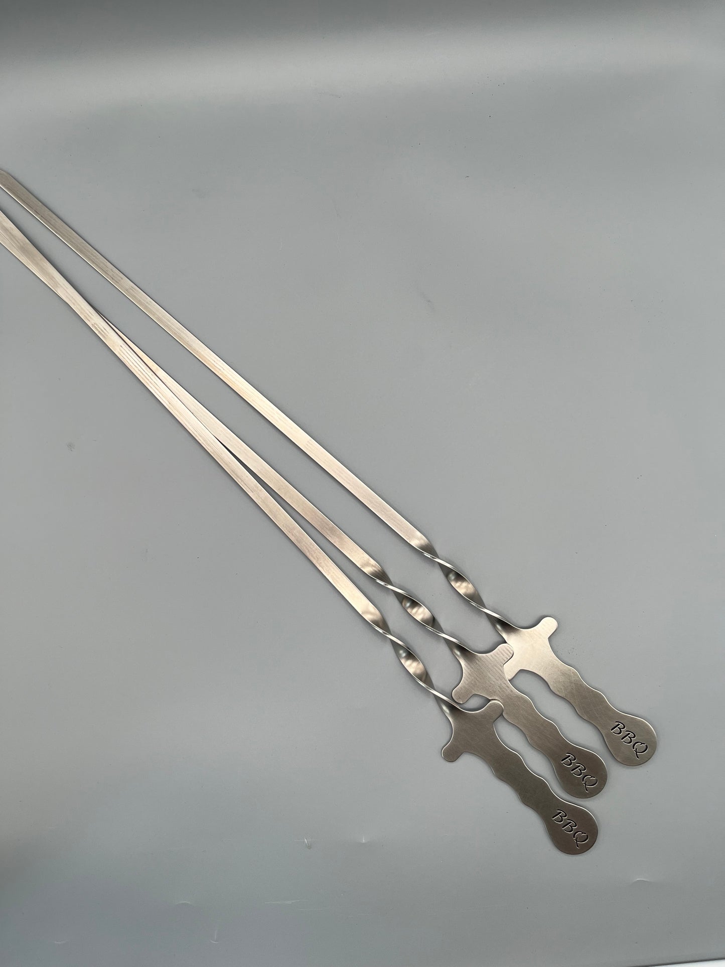 drei lange gedrehte Spieße mit BBQ Schrift im Griff