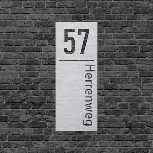 Schild aus Stahl. Abgetrennt durch eine Linie steht oben die Zahl und unter der Linie steht der Straßenname schmaler und senkrecht. Schild hängt an einer Hauswand.