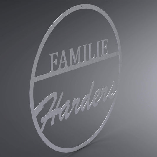 Dünner, ausgehöhlter Kreis. Oben steht in Druckbuchstaben auf einer Linie: "Familie". Da drunter steht verschnörkelt der Familienname. Seitliche Ansicht.