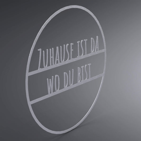 Dünner, ausgehöhlter Kreis. In der Mitte steht: "Zuhause ist da wo du bist". Seitliche Ansicht.