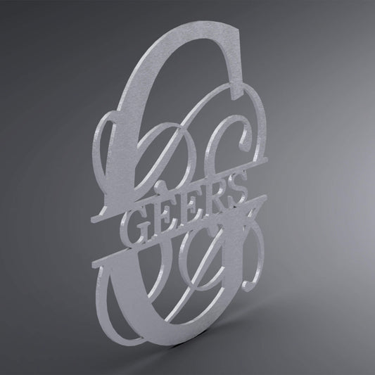 Eine Wanddekoration. Großer verschnörkelter Buchstabe mit einem Geflecht verziert. In der Mitte steht der Familienname. Seitliche Ansicht.