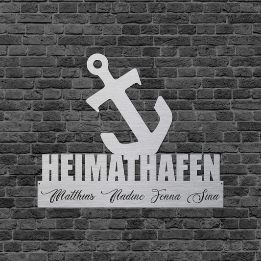 Eine Wanddekoration mit einem Anker, den Spruch Heimathafen und eingravierte, individuelle Namen. Schild hängt an einer Hauswand.