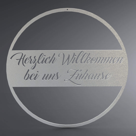 Runder Kranz, in der Mitte ist ein Balken mit der Schrift Herzlich Willkommen bei uns Zuhause.