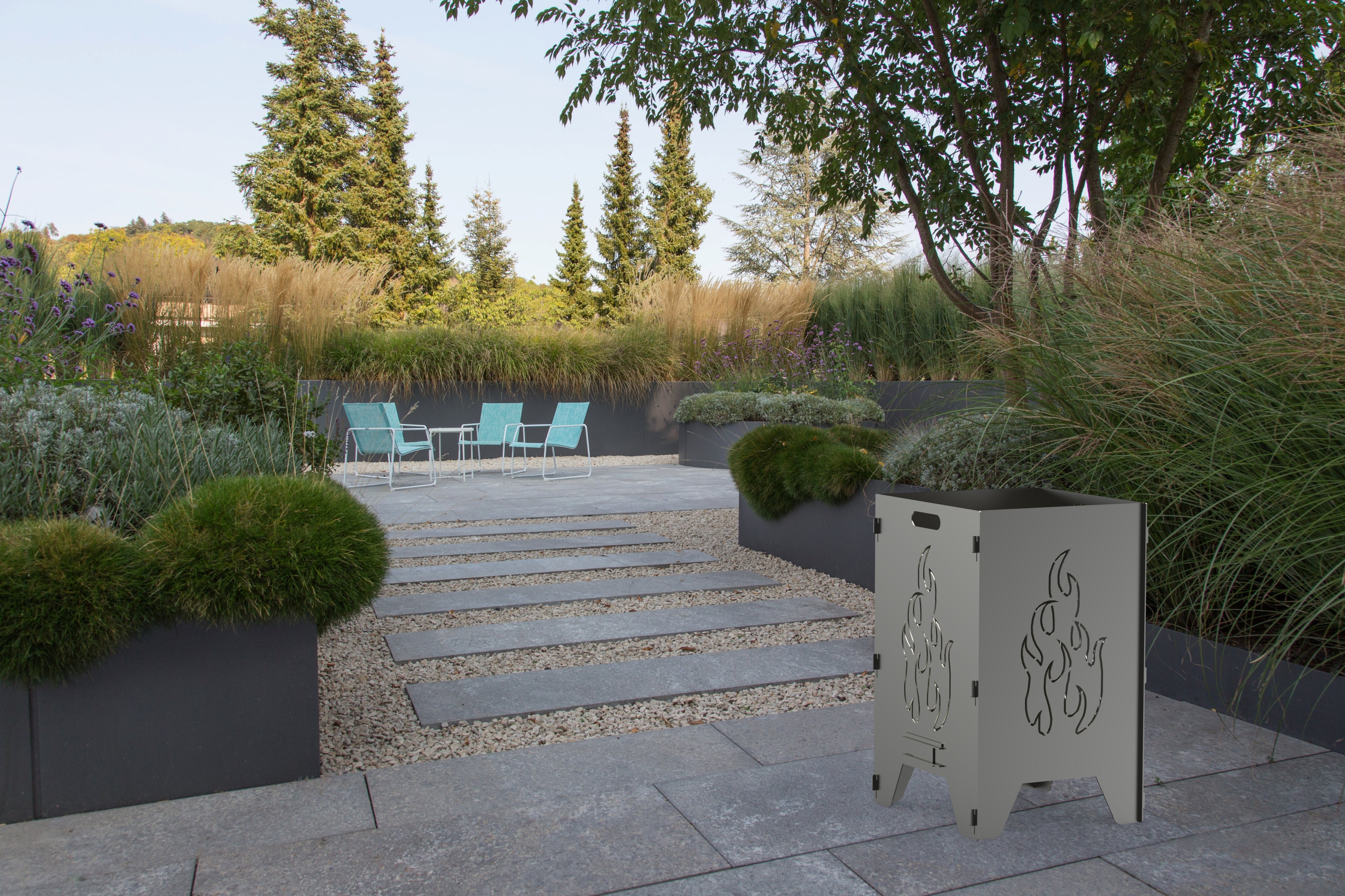 Eine Feuertonne mit dem Flammenmotiv steht in einer Gartenlandschaft. 