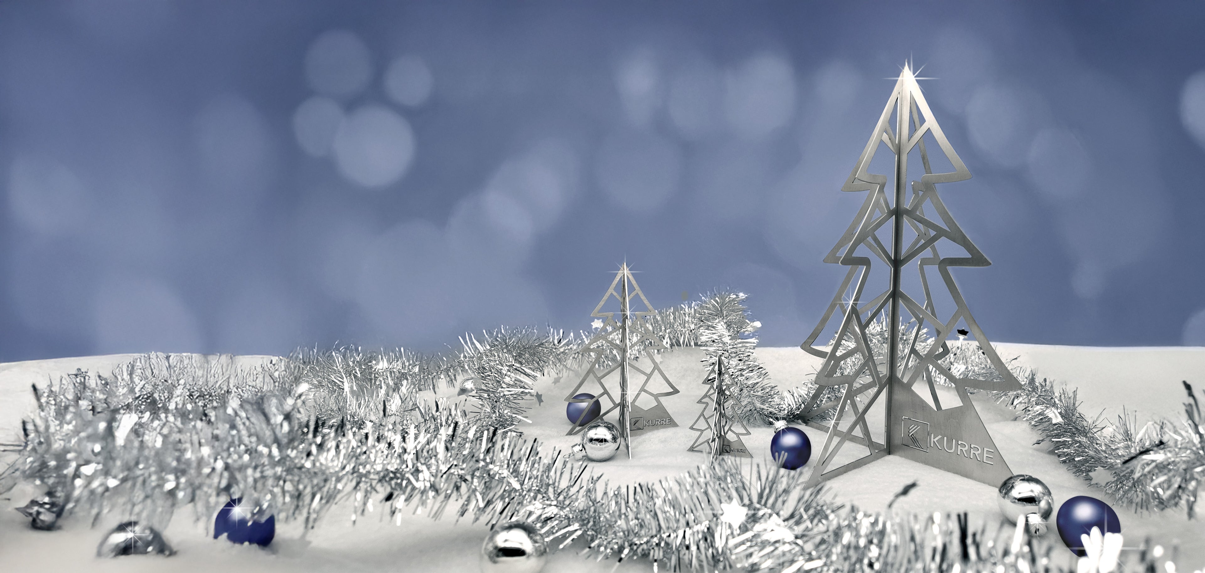 Weihnachtsbäume in Silber (Metall) in einer Kulisse aus Schnee, Weihnachtskugeln und Lametta.