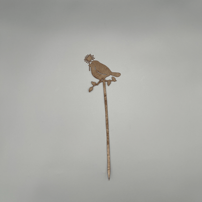 Liebevoll gestaltete Metallstecker zeigt einen Ast, auf dem ein Vogel mit Blume im Schnabel Platz genommen hat.