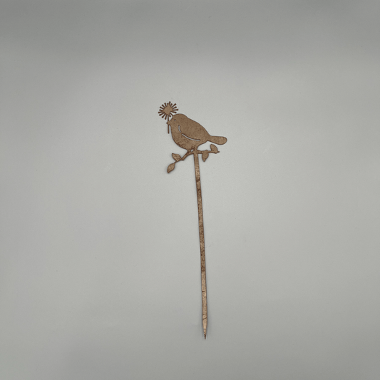 Liebevoll gestaltete Metallstecker zeigt einen Ast, auf dem ein Vogel mit Blume im Schnabel Platz genommen hat.