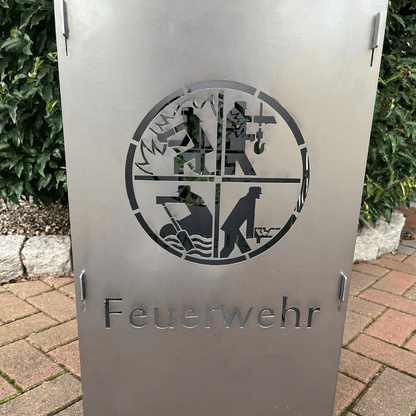 Aus gelasertes Feuerwehrwappen in einer Metall Feuertonne. Schriftzug Feuerwehr unter dem Wappen auf der Feuertonne. 