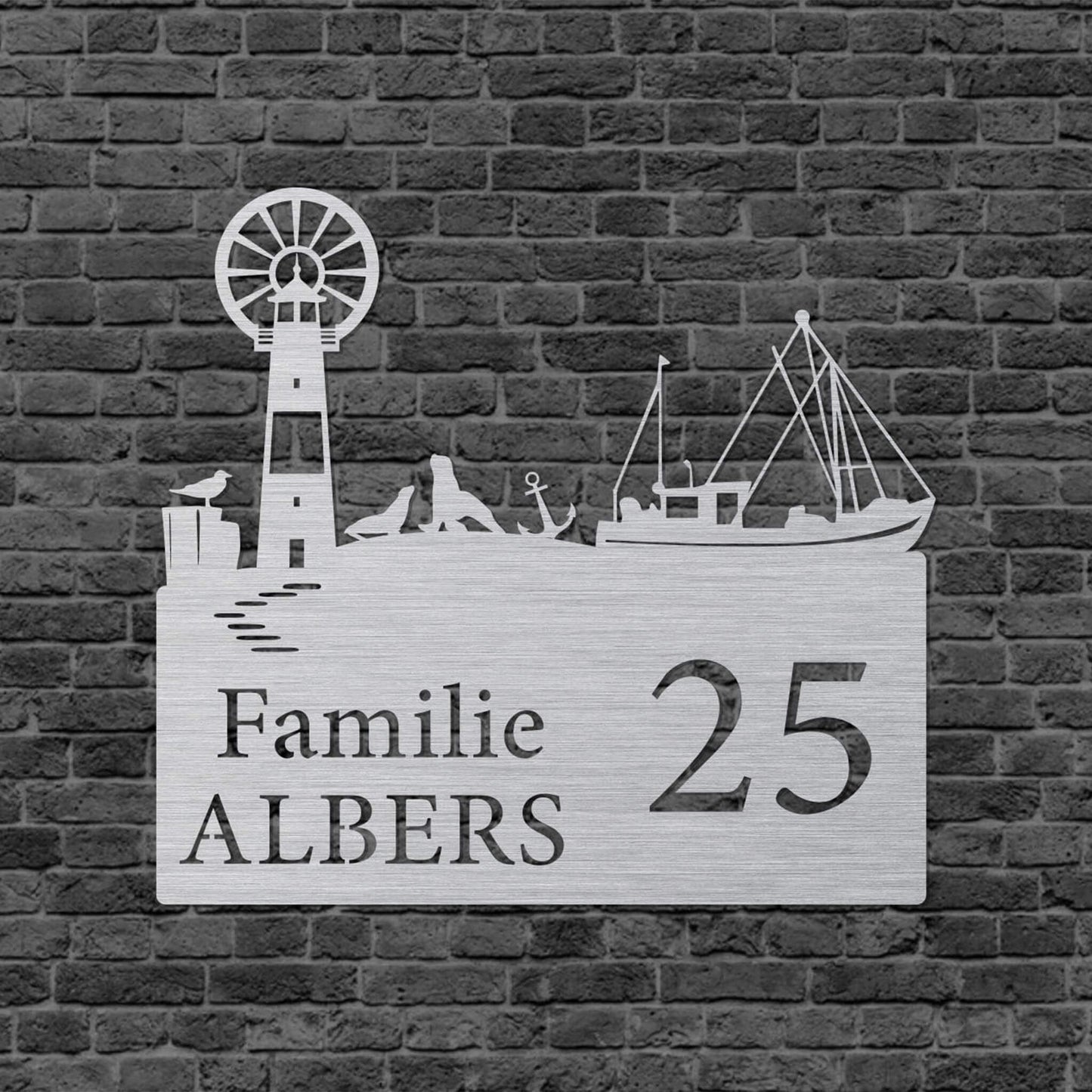 Eine Wanddekoration in Form eines Rechtecks. Rechts steht Familie und darunter der Familienname. Links steht die vergrößerte Hausnummer. Auf der oberen Kante ist eine Leuchtturm, ein Schiff, ein Anker, eine Möwe und Seelöwen abgebildet. Das Schild hängt an einer Hauswand.