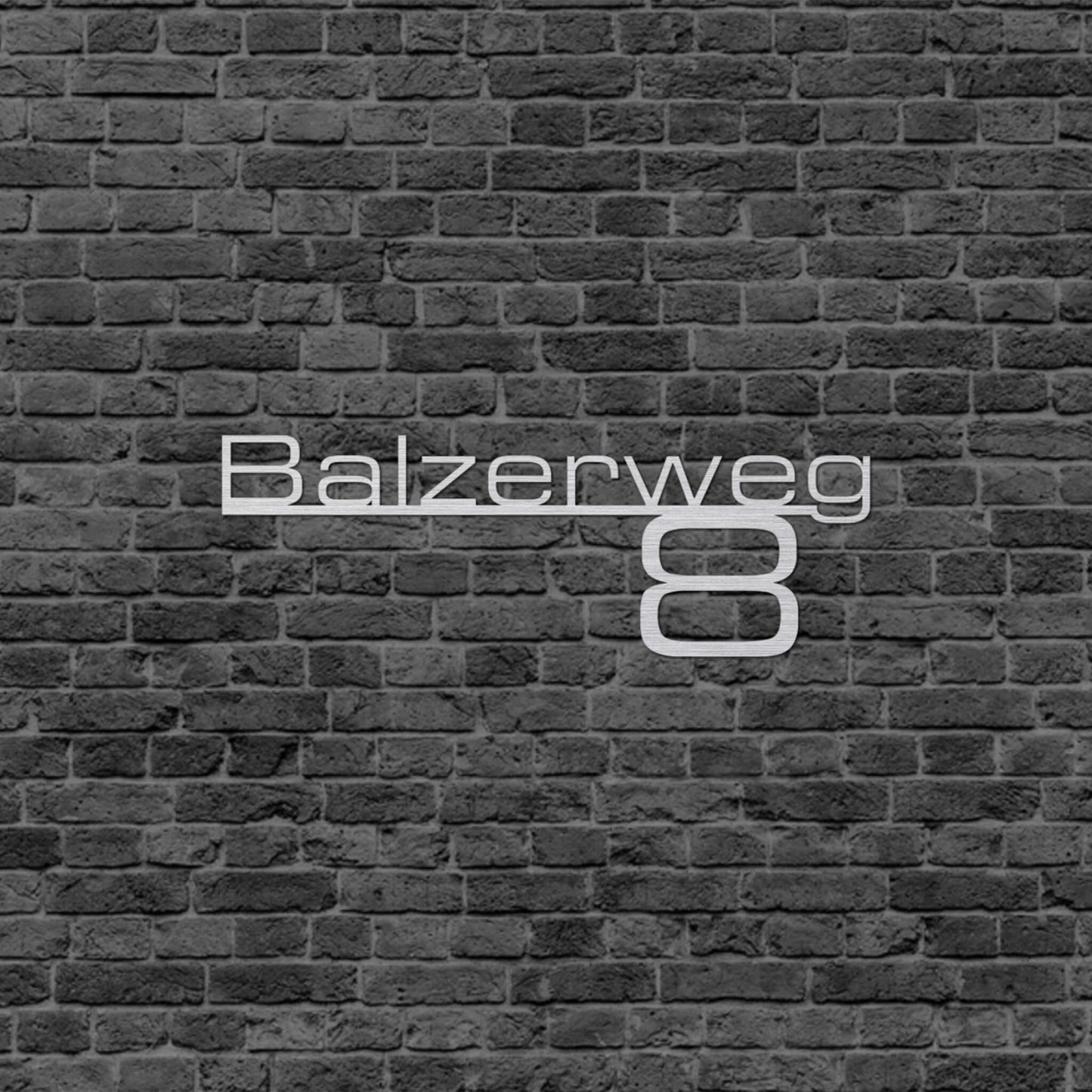 Eine Wanddekoration die die Adresse wiedergibt. Straßenname steht auf einer schmalen Linie und da drunter steht die Hausnummer. Schild hängt an einer Hauswand.