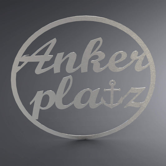 Dünner, ausgehöhlter Kreis. Über die komplette Lücke steht: "Ankerplatz" groß und verschnörkelt. Das t wurde gegen einen Anker ersetzt.