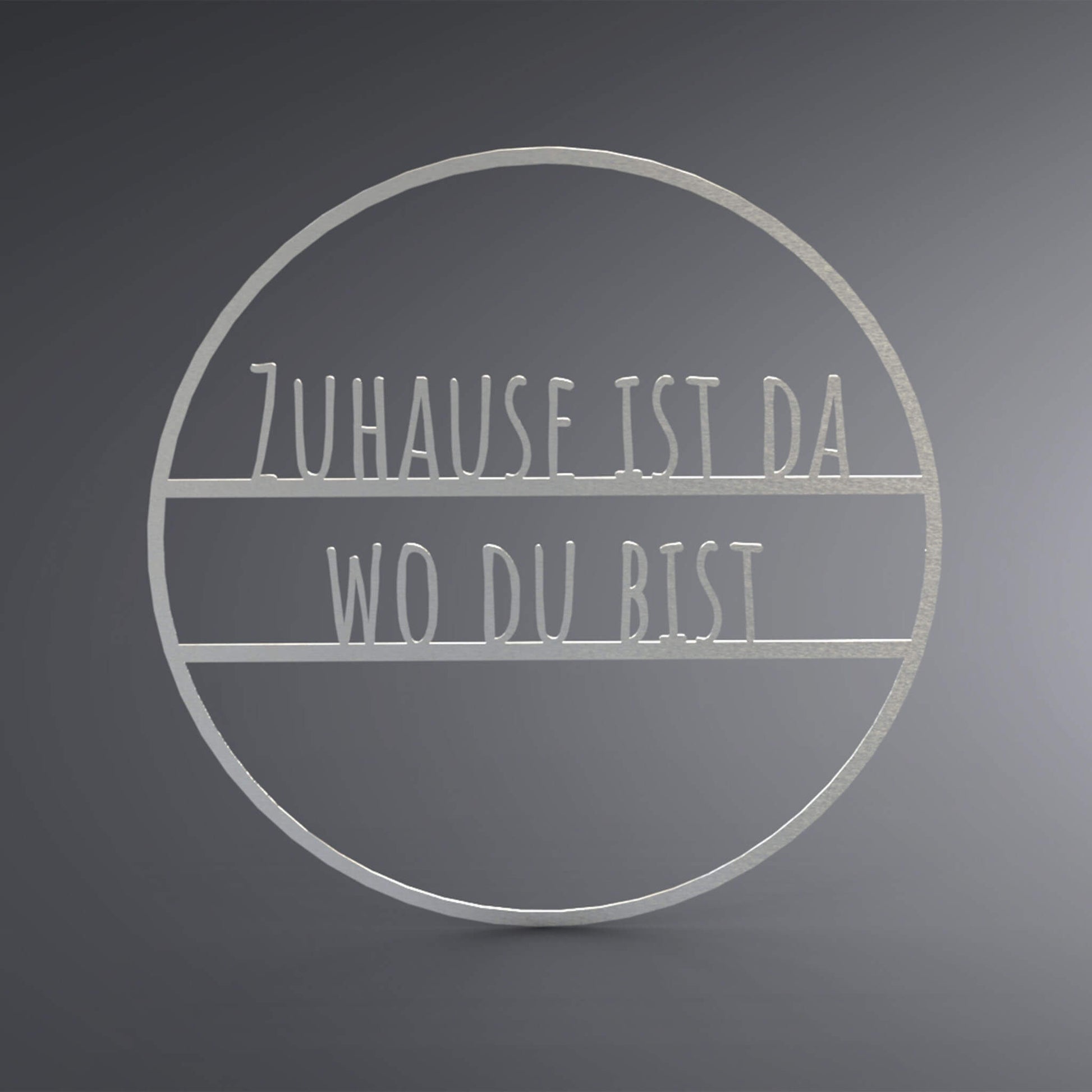 Dünner, ausgehöhlter Kreis. In der Mitte steht: "Zuhause ist da wo du bist".