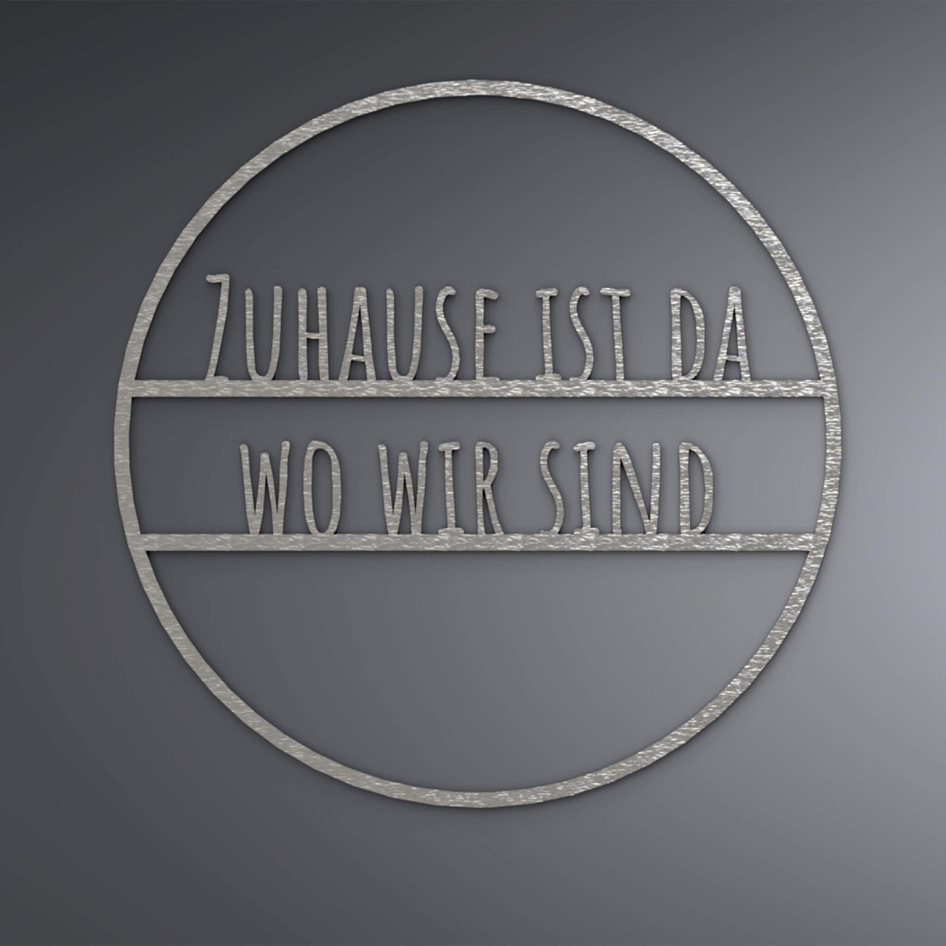 Dünner, ausgehöhlter Kreis. Mittig steht: "Zuhause ist da wo wir sind", auf schmalen Linien. 
